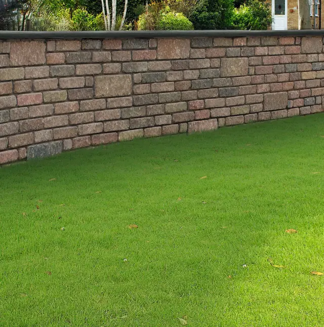 Neat garden wall made of irregular pink and grey stone blocks with a well-maintained green lawn in front.
